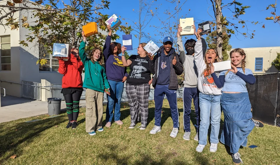 A group of people holding up books in front of a building.