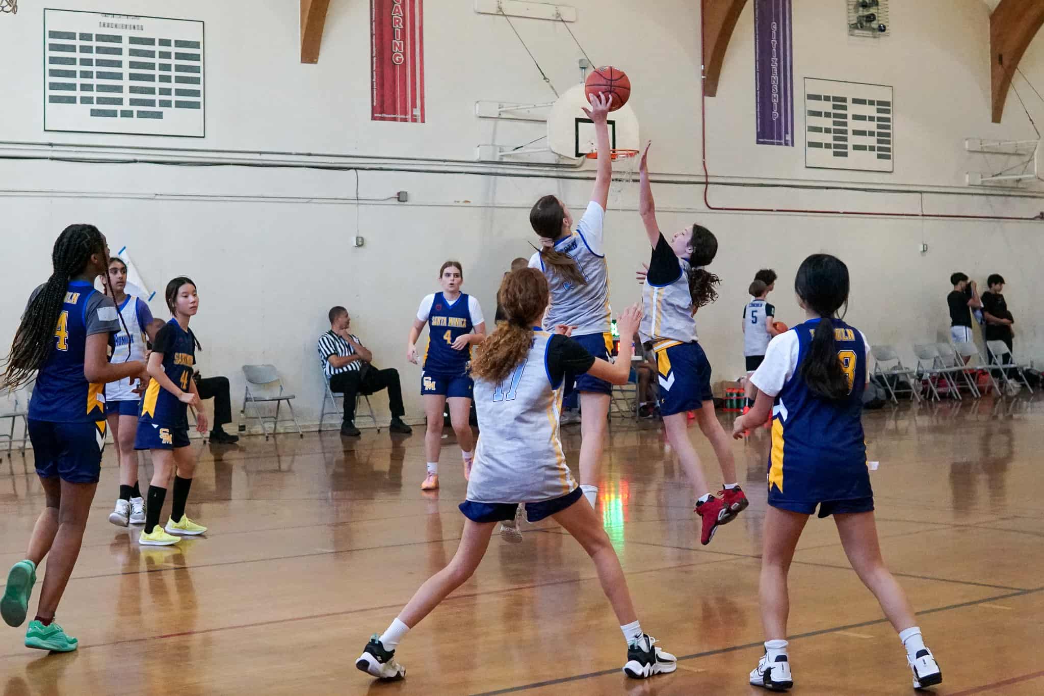 A group of girls playing basketball in a gym.