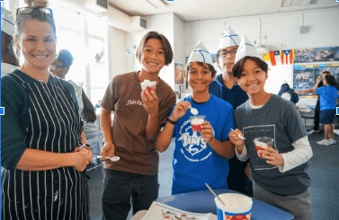 Three girls smile for a photo while working on an art project