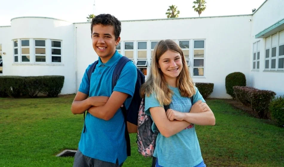 A boy and girl standing in front of a school building.