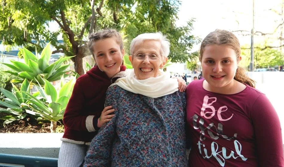 Two young girls posing for a photo with an elderly woman.