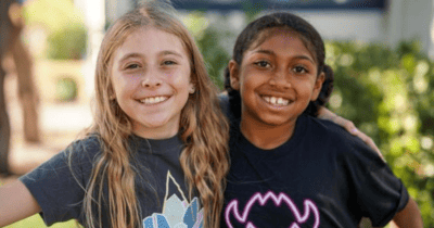 Two young girls smiling while wearing t - shirts.
