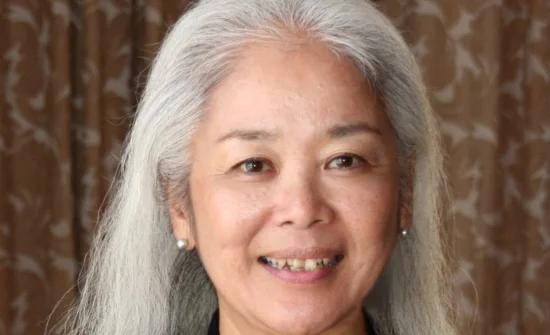 An asian woman with white hair smiling for the camera.