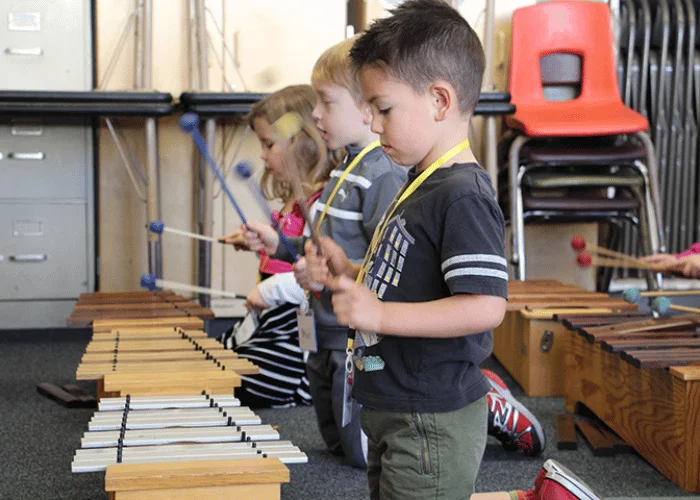 A group of children playing xylophones in a classroom.