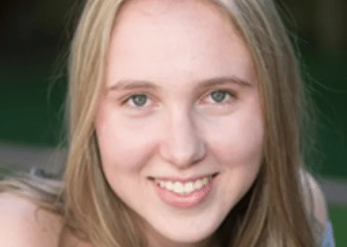 A young girl with long blonde hair smiling for the camera.