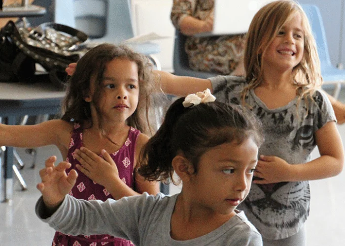 A group of young girls are dancing in a classroom.