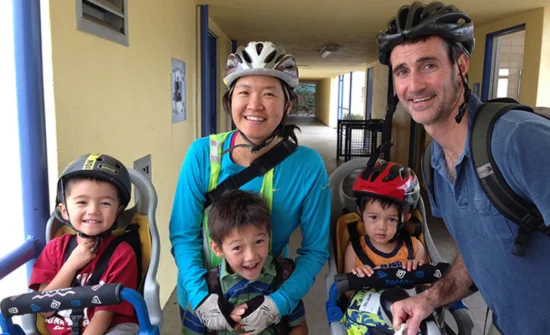 A family with two children in bicycle helmets posing for a photo.