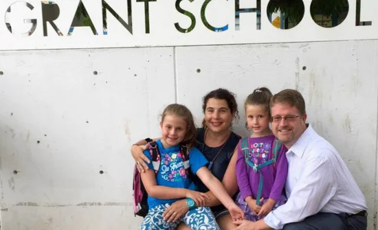 A family posing in front of a sign that says grant school.