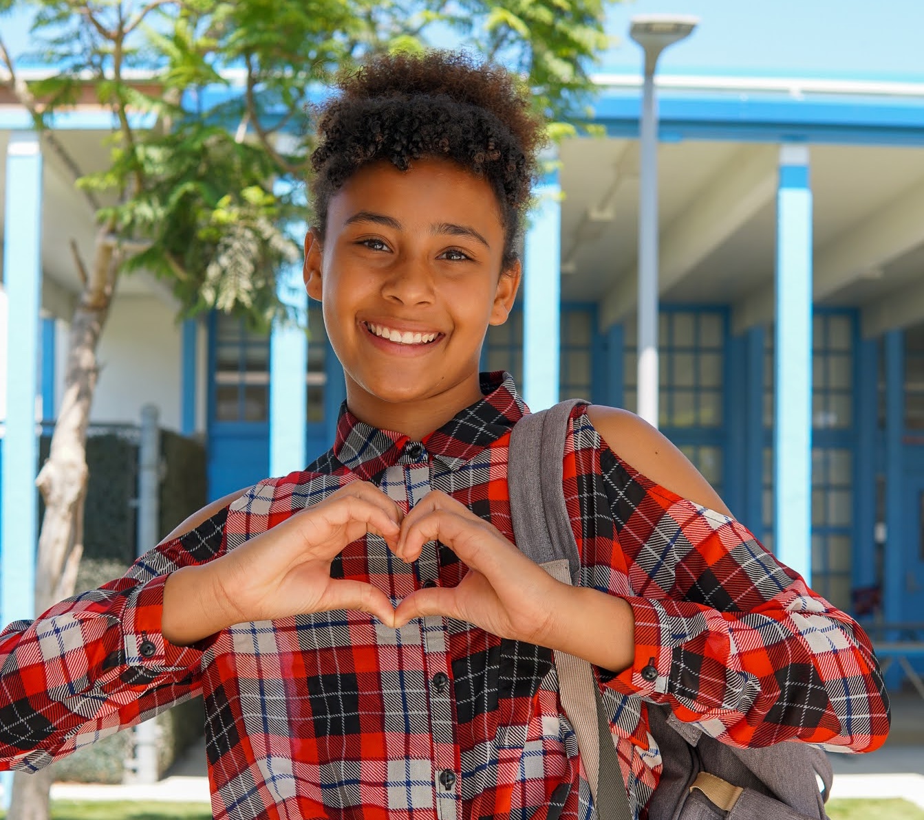 Two young girls making a heart with their hands.